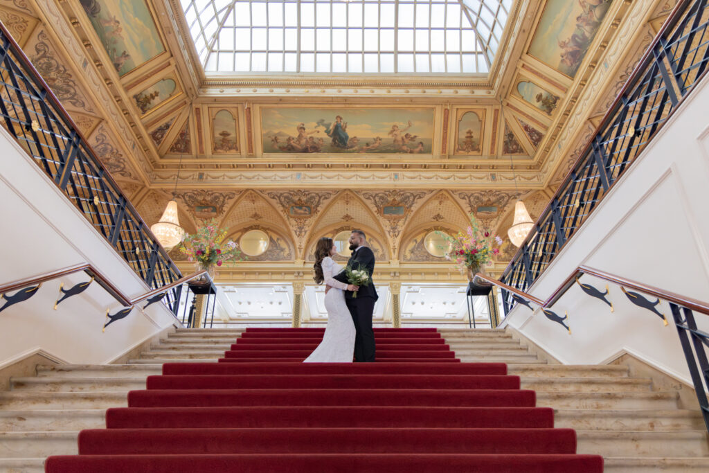 Luxury Fine Art trouwfotografie - bruidspaar op grand staircase in historisch gebouw met gouden plafond