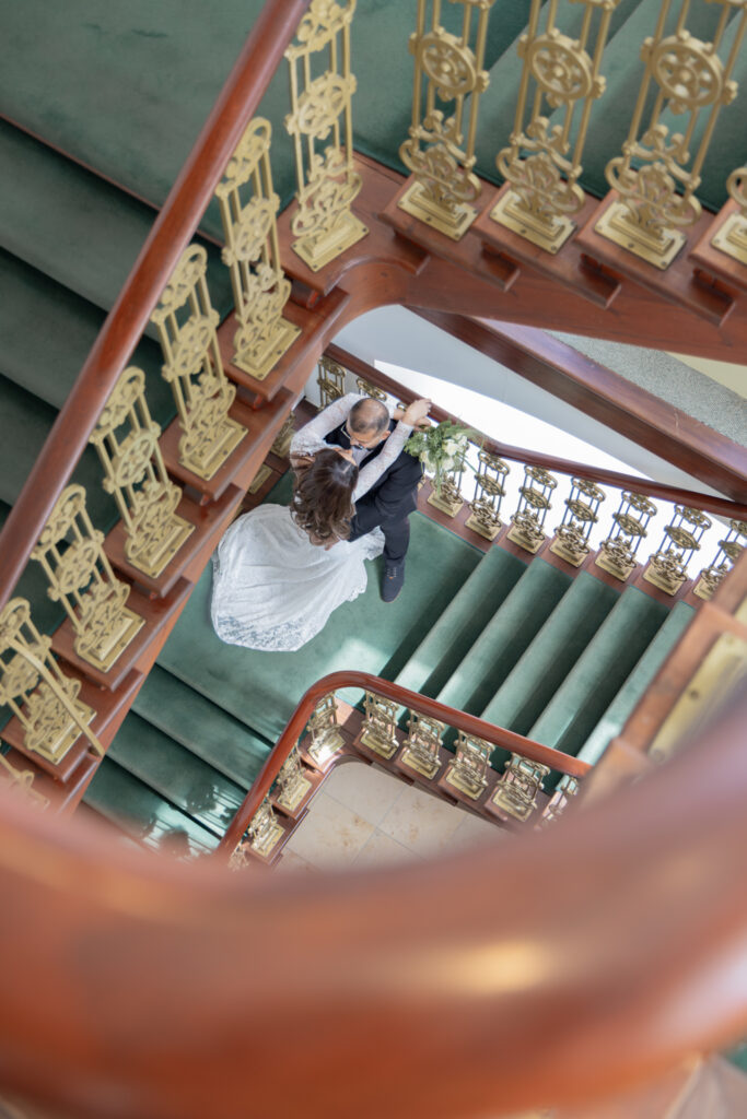 Artistieke Fine Art trouwfotografie - bruidspaar op grand staircase vastgelegd vanuit vogelperspectief