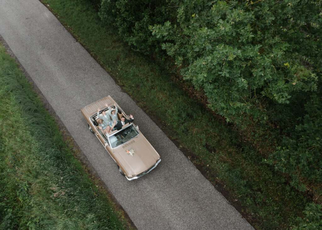 Bruidspaar in auto met drone gefotografeerd, drone foto van bruidspaar in trouwauto, bizarre bruiloft, trouwfotograaf LM Weddings, trouwfotograaf Drenthe